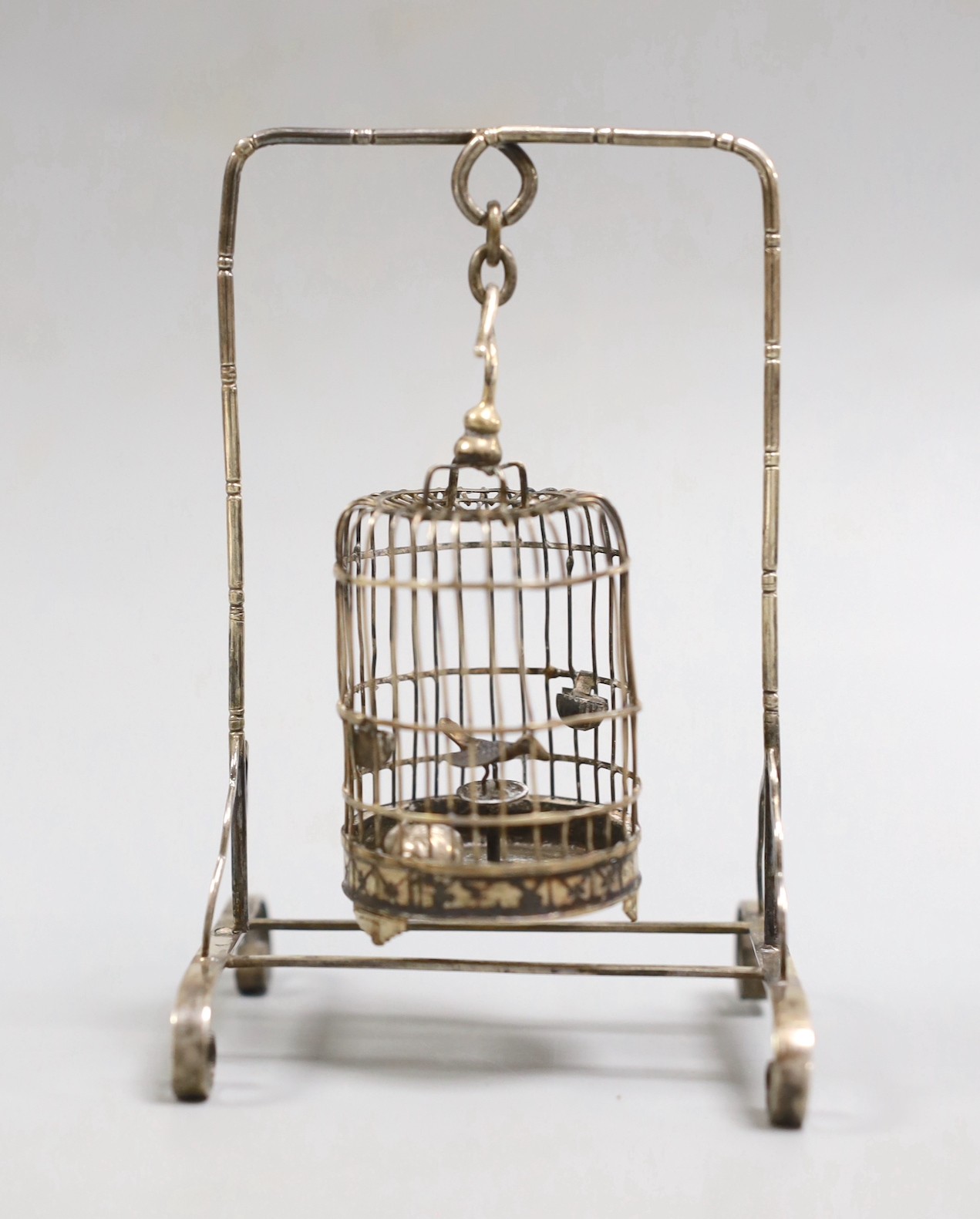 A Chinese white metal miniature model of a bird cage and stand, height 11.8cm, and a miniature teapot.